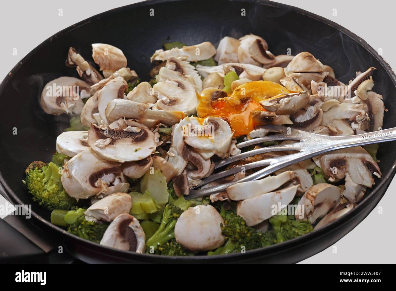 Vegane Gemüseküche Brokkoli, Champignons, Zucchini und Grünkohl während der Zubereitung in einer Bratpfanne *** Vegan Gemüseküche Brokkoli, Pilze, Zucchinis und Grünkohl während der Zubereitung in einer Pfanne Stockfoto