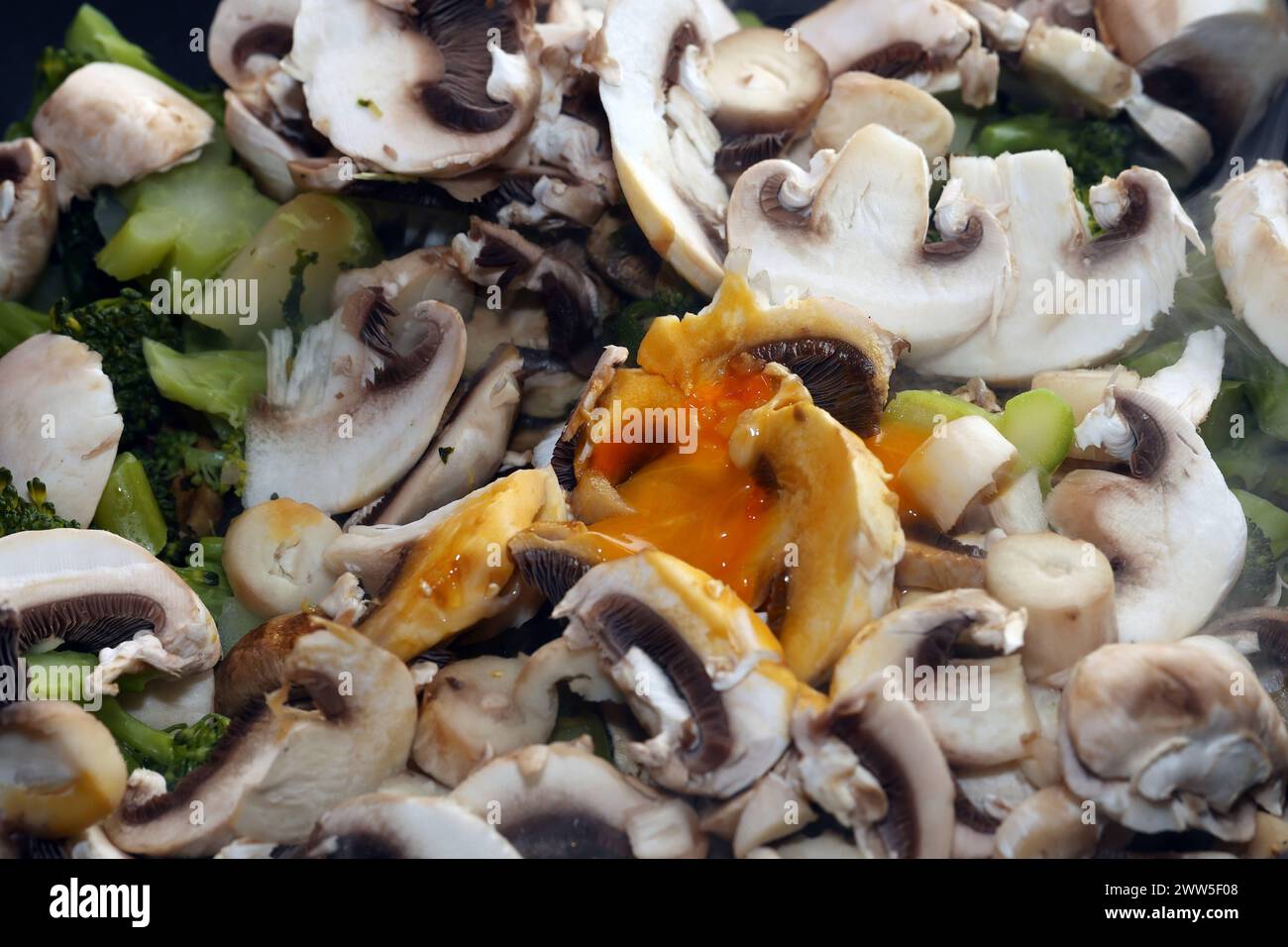 Vegane Gemüseküche Brokkoli, Champignons, Zucchini und Grünkohl während der Zubereitung in einer Bratpfanne *** Vegan Gemüseküche Brokkoli, Pilze, Zucchinis und Grünkohl während der Zubereitung in einer Pfanne Stockfoto