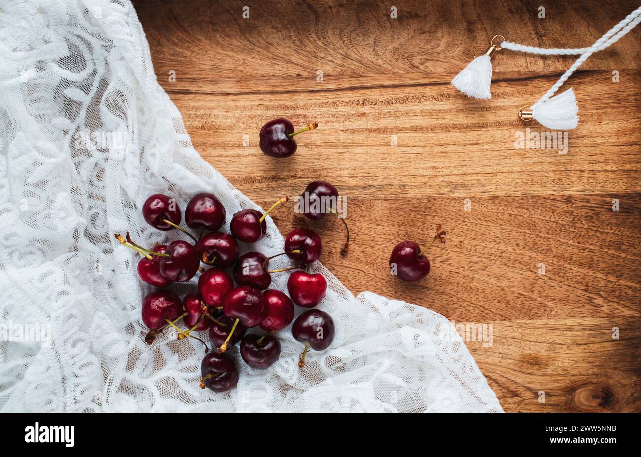 Süße Kirschen auf einer Serviette aus Spitze auf einem Holztisch. Stockfoto