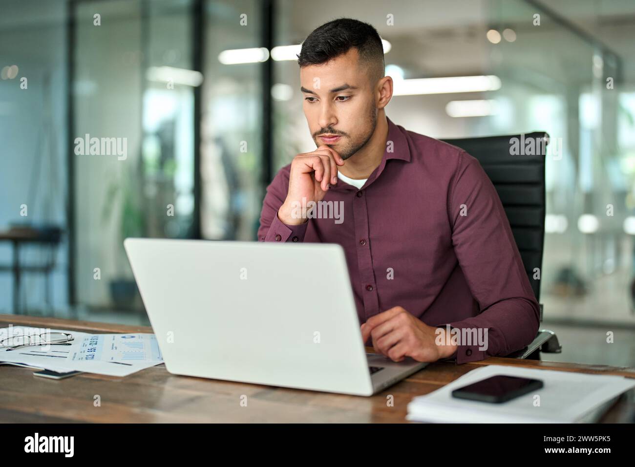 Geschäftiger Geschäftsmann aus Lateinamerika, der an einem Laptop arbeitet und am Schreibtisch sitzt. Stockfoto