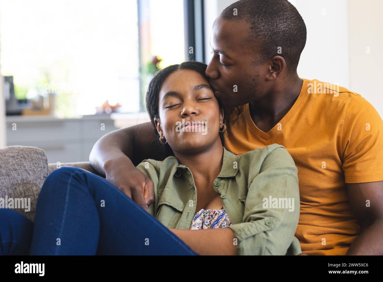 Ein afroamerikanisches Paar teilt sich einen zärtlichen Moment auf der Couch zu Hause Stockfoto