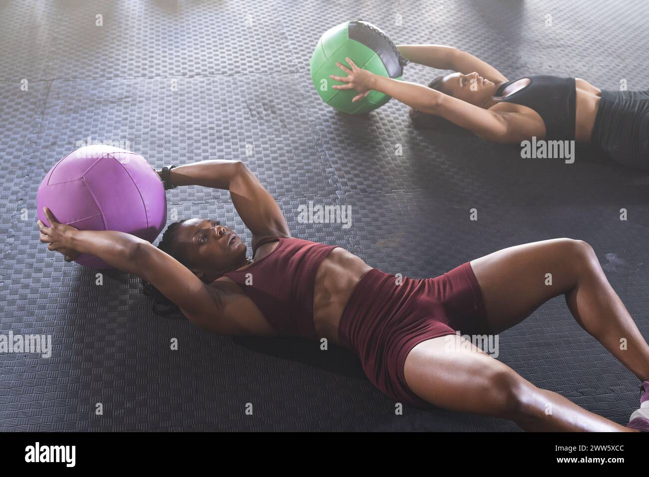 Eine afroamerikanische starke Frau demonstriert eine Übung mit einem Medizinball Stockfoto