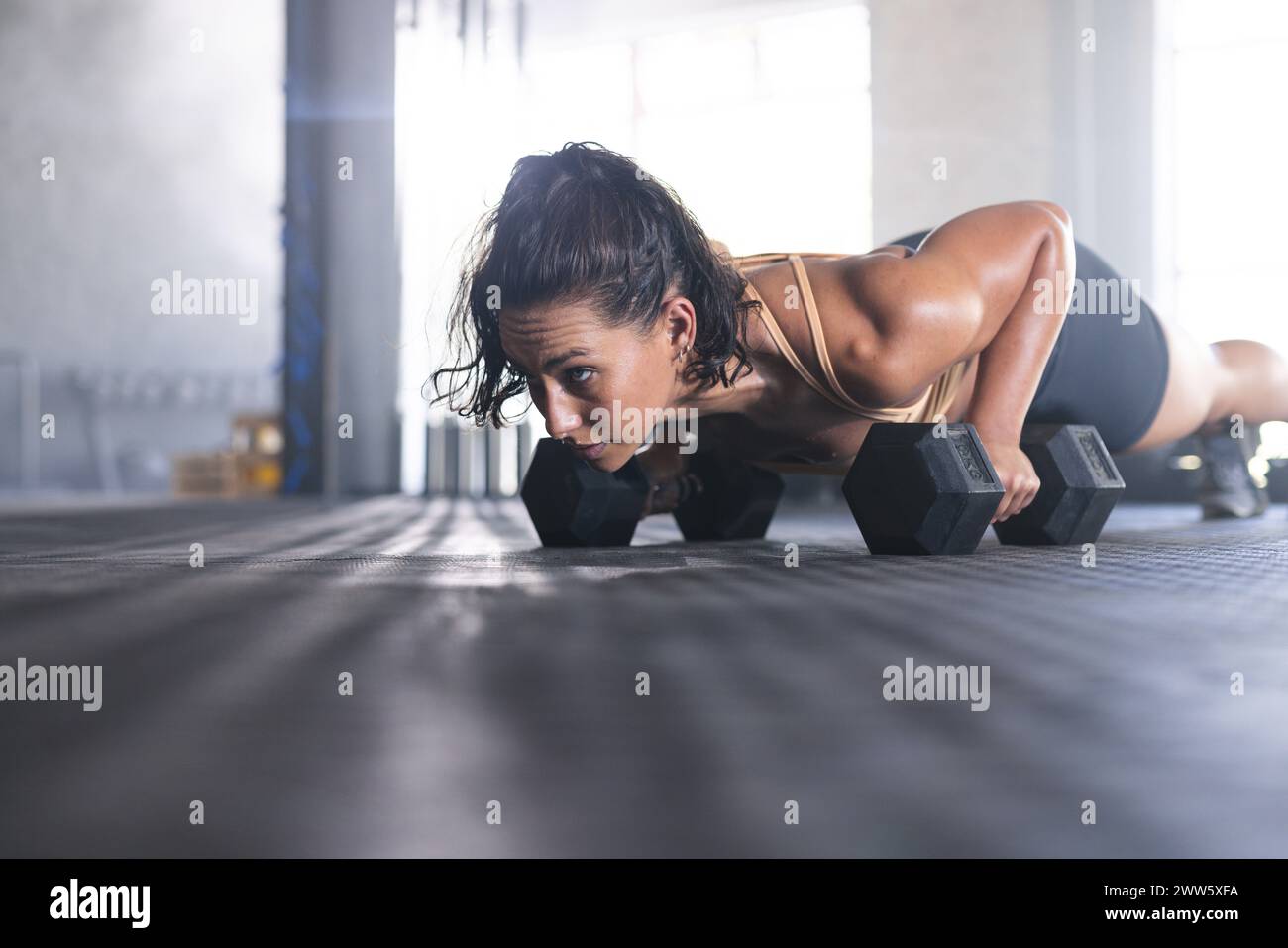 Eine fitte Kaukasierin übt im Fitnessstudio Krafttraining mit Kurzhanteln aus Stockfoto