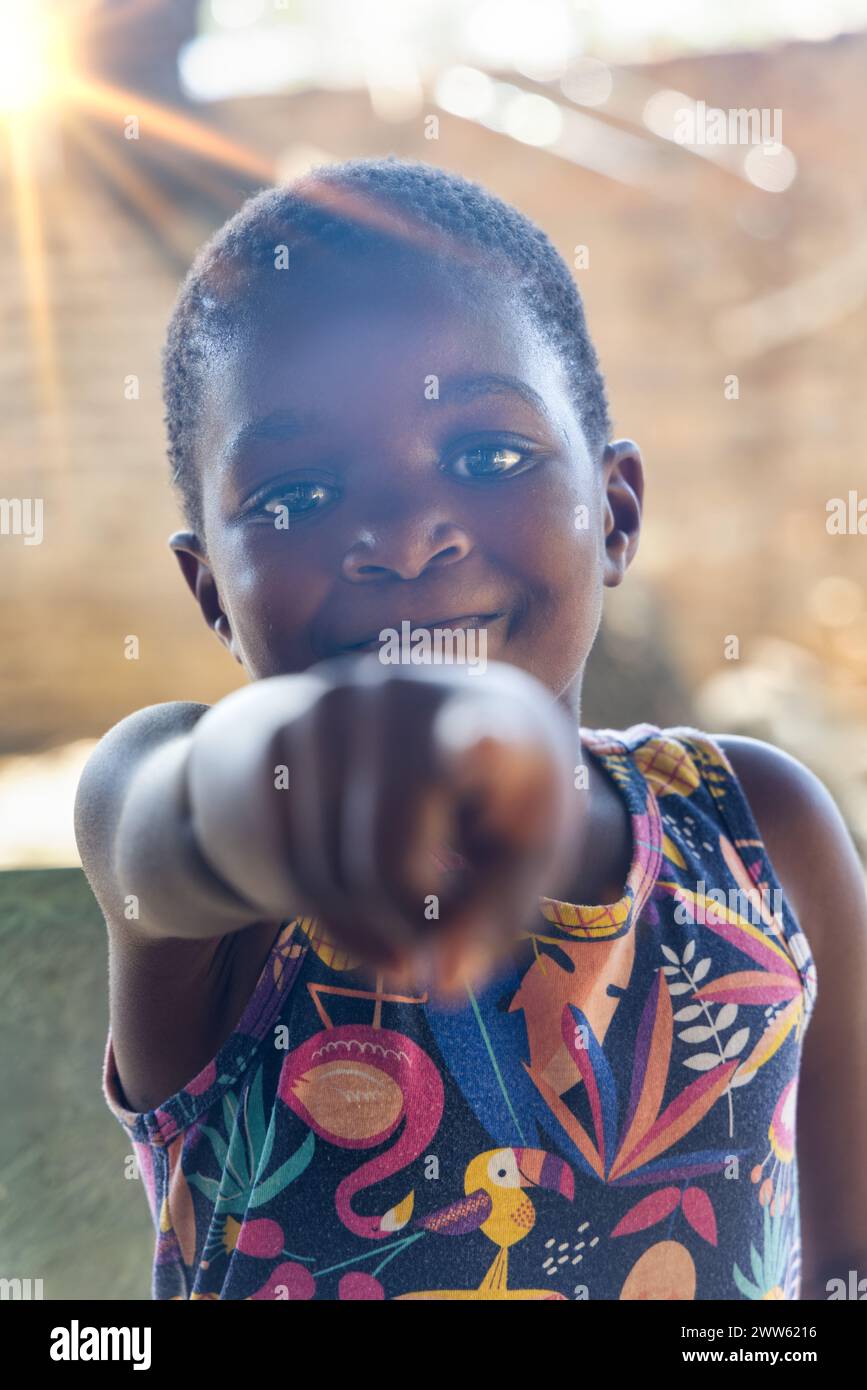 Lächelndes afroamerikanisches Mädchen, gestikulierend, mit dem Finger nach vorne zeigend, bist du es, spielst draußen im Garten Stockfoto