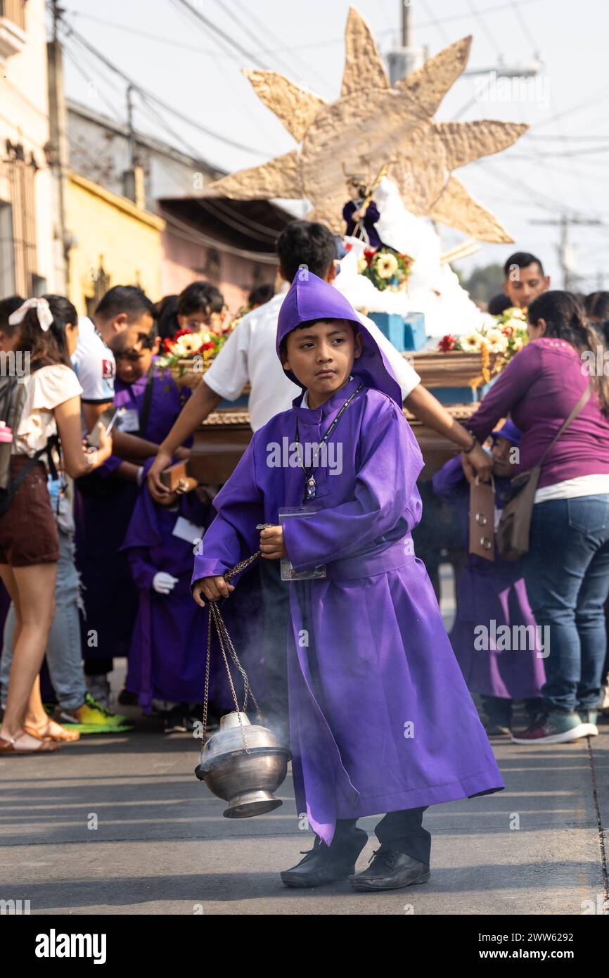 Antigua, Guatemala. März 2024. Ein junger guatemaltekischer Junge führt eine Prozession mit Weihrauch, während Kinder lernen, wie man einen religiösen Palanquin vor Beginn der Heiligsten Woche, 21. März 2024 in Jocotenango, Guatemala, trägt. Die opulenten Prozessionen, detailgetreuen Alfombras und jahrhundertealten Traditionen ziehen mehr als 1 Million Menschen in die alte Hauptstadt. Quelle: Richard Ellis/Richard Ellis/Alamy Live News Stockfoto