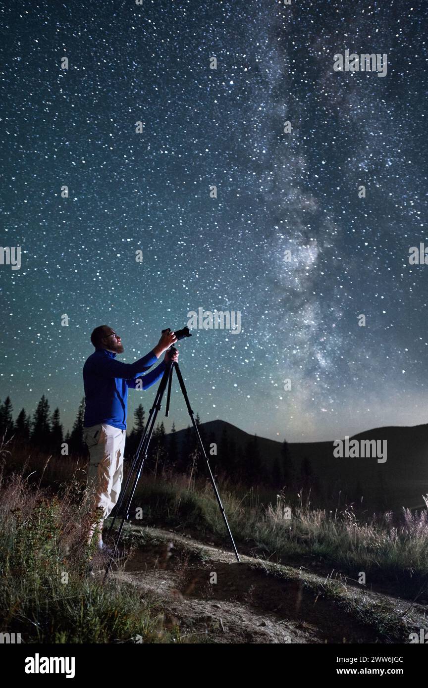 Professioneller Fotograf, der Fotos von der Milchstraße macht. Junger Mann, der seine Kamera fokussiert, um ein perfektes Bild des Sternenhimmels zu machen. Ein Mann, der Bilder vom Nachthimmel voller Sterne in den Bergen macht. Stockfoto