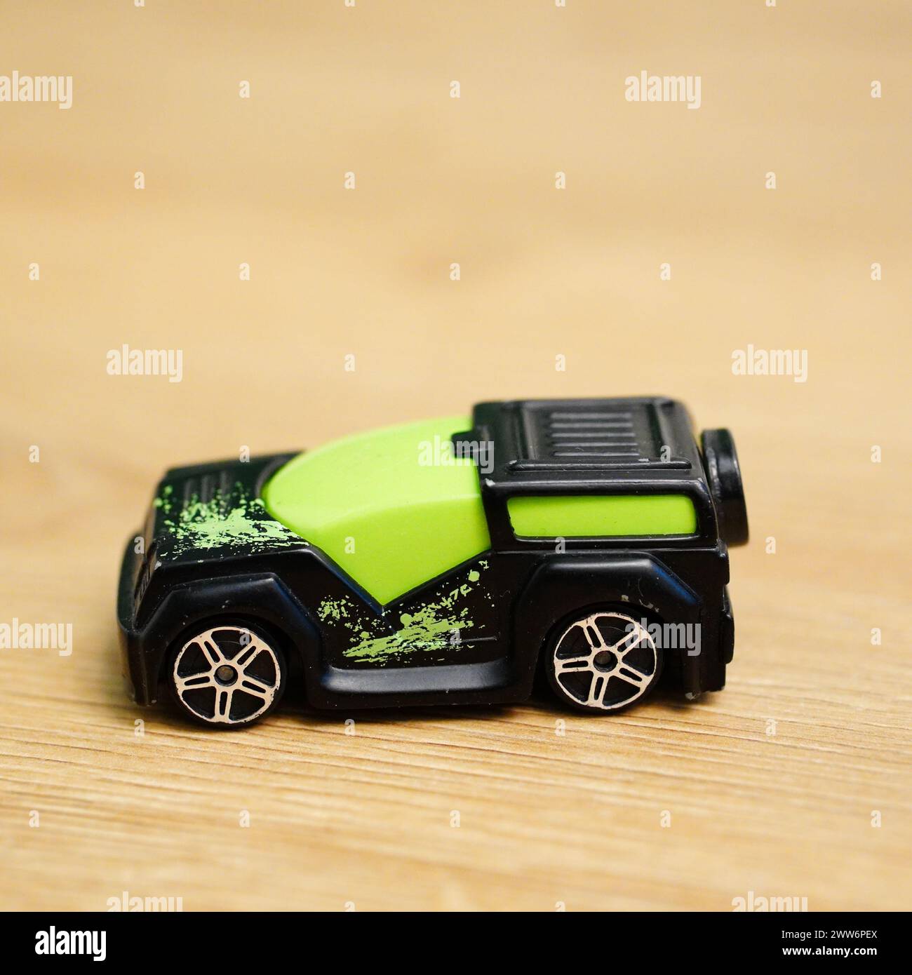 Ein grünes und schwarzes Spielzeugauto auf einer Holzoberfläche Stockfoto