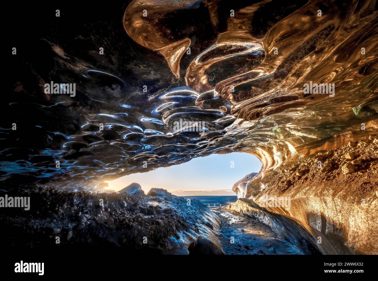 Im Inneren der Eishöhle zeigen die durchscheinenden Wände die Blautöne, die zwischen dem blasssten Azurblau und dem tiefsten Saphir tanzen und von warmem Sonnenlicht durchströmt werden Stockfoto