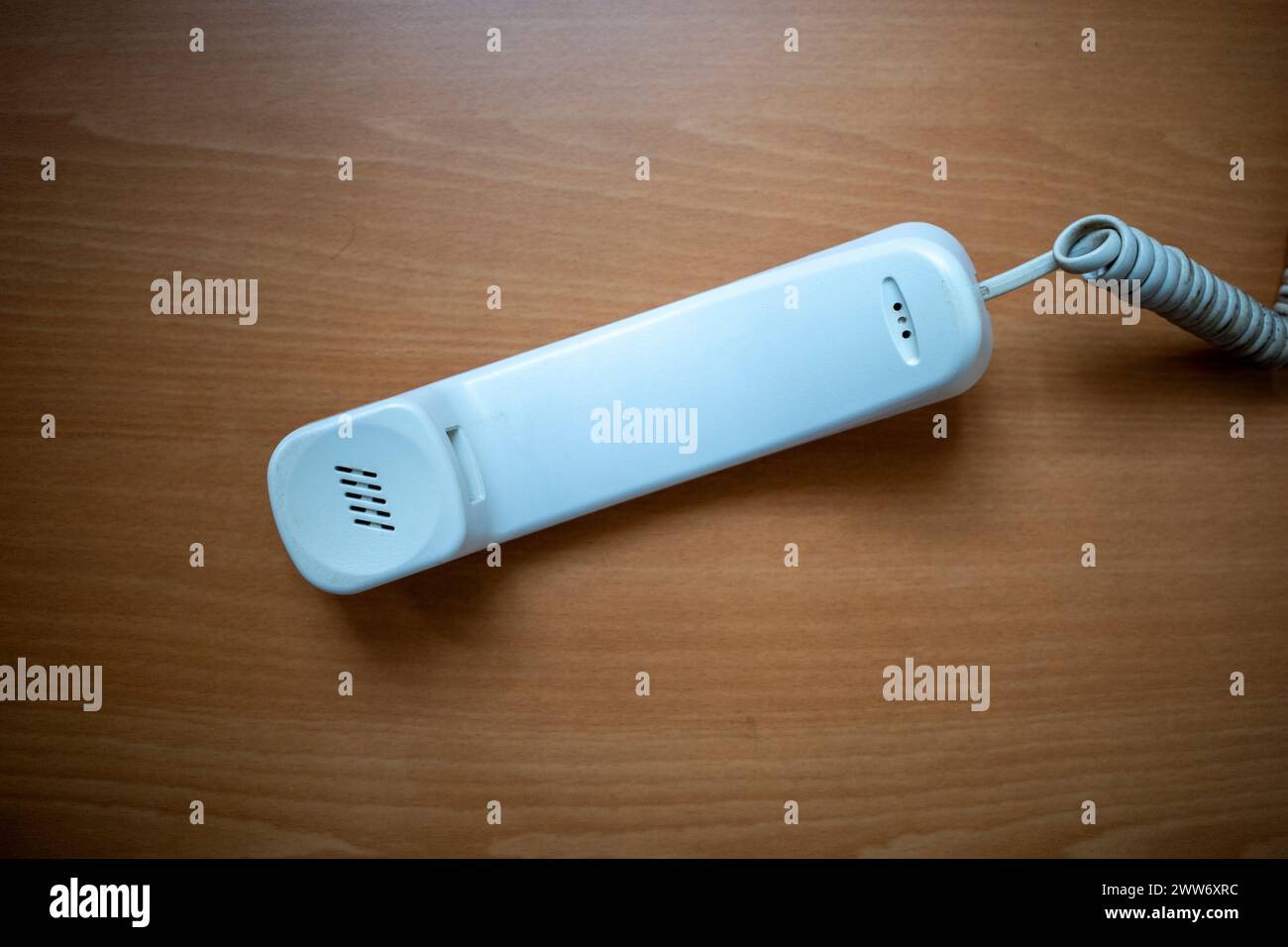 Weißes Handset des Festnetztelefons auf Holztisch. Hintergrund des Telekommunikationskonzepts. Stockfoto