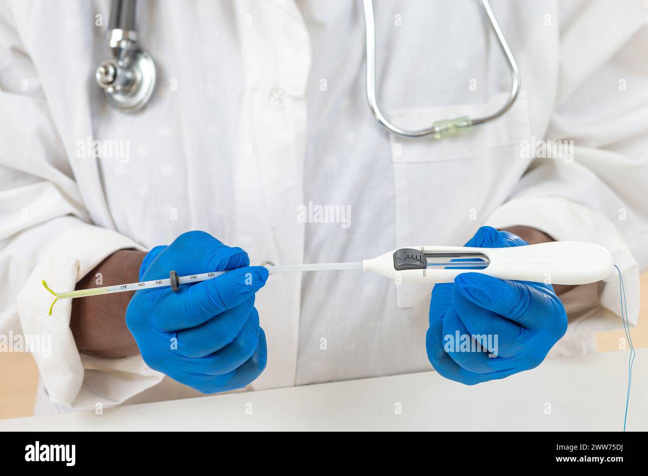 Arzt hält die vollständige hormonelle IUD bereit, um sie auf eine weibliche Patientin zu legen. Stockfoto