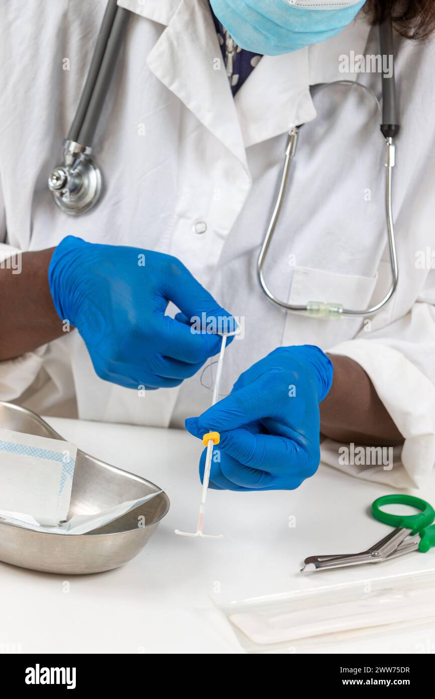 Arzt hält die vollständige hormonelle IUD bereit, um sie auf eine weibliche Patientin zu legen. Stockfoto