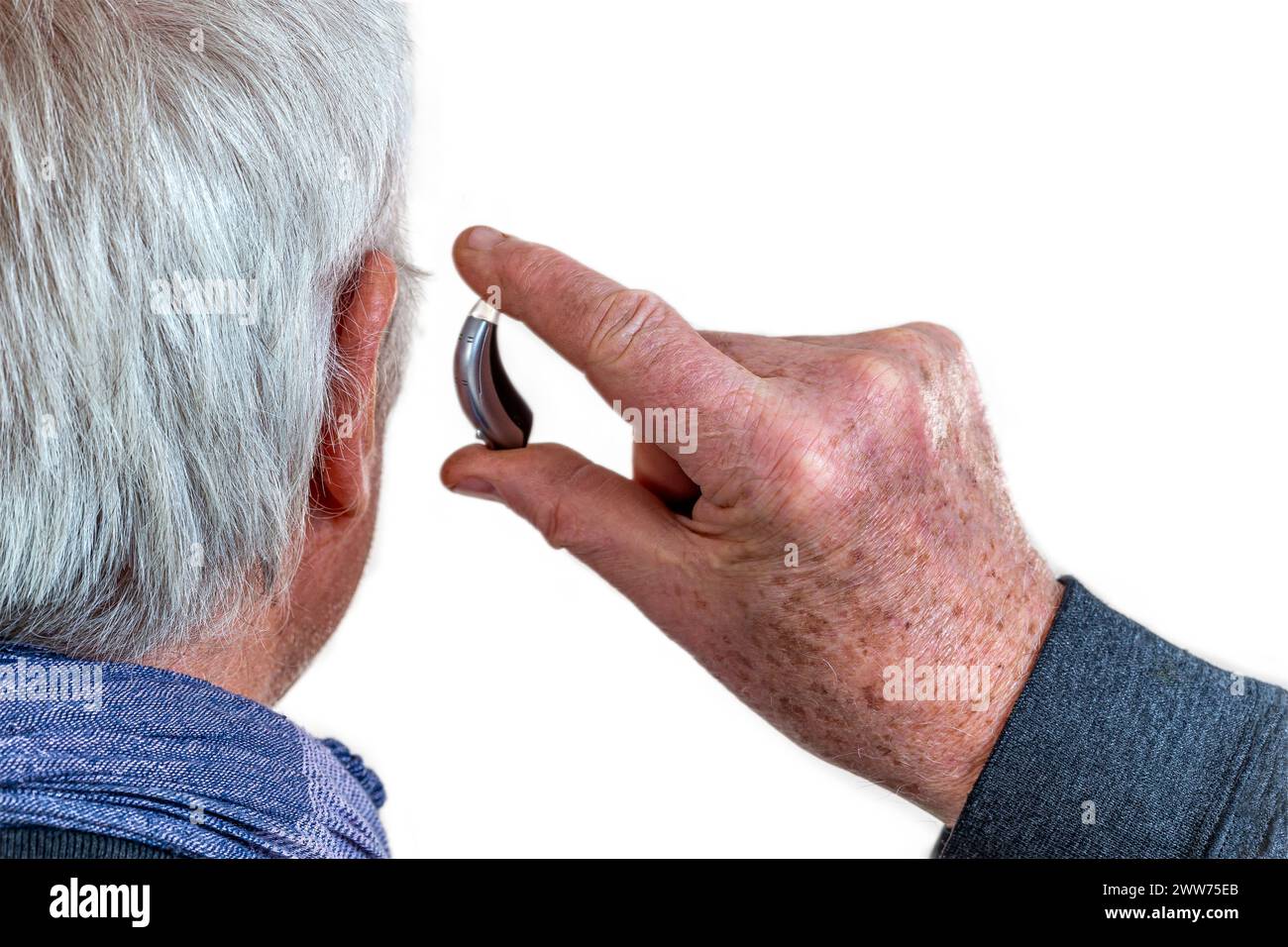 Amerikanischer Schuss, ein Hörgerät an einen weißhaarigen Senioren anzubringen, Rückansicht. Stockfoto
