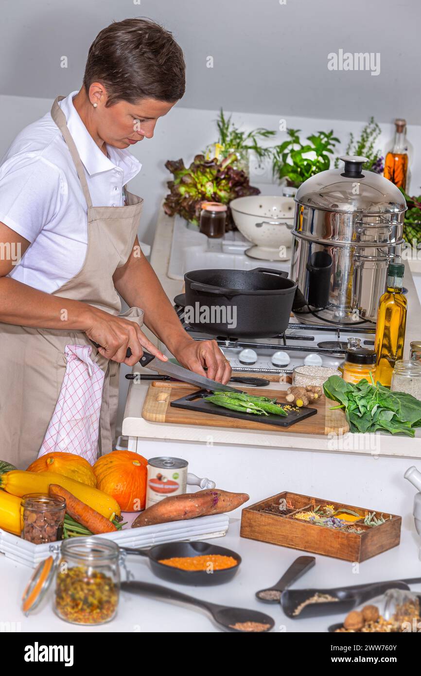 Junge Frau, Messer in der Hand, Gemüse hacken. Stockfoto