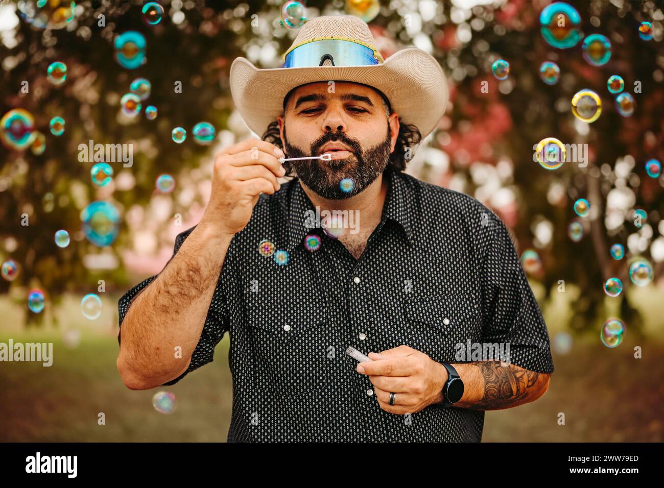Ein Cowboy, der Blasen in einem Park bläst Stockfoto