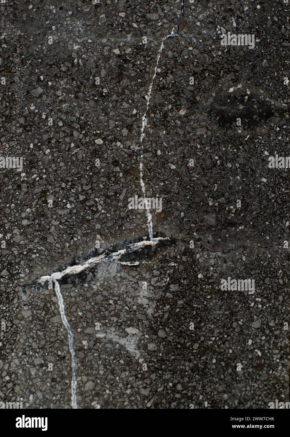 Oberfläche einer schwarz-grauen Steinsäule mit weißen Spaltlinien, die die Linien eines menschlichen Gesichtes nachahmen, und einem schwarzen Augenfleck oben rechts Stockfoto