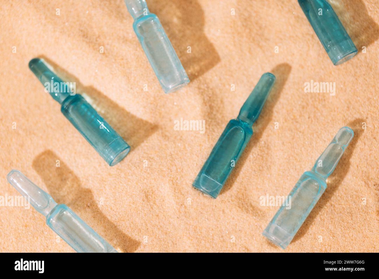 Nahaufnahme von blauen Ampullen mit intensivem Feuchtigkeitskonzentrat mit Hyaluronsäure und Vitaminen auf Sandgrund. Set von Gesichtsseren mit p Stockfoto