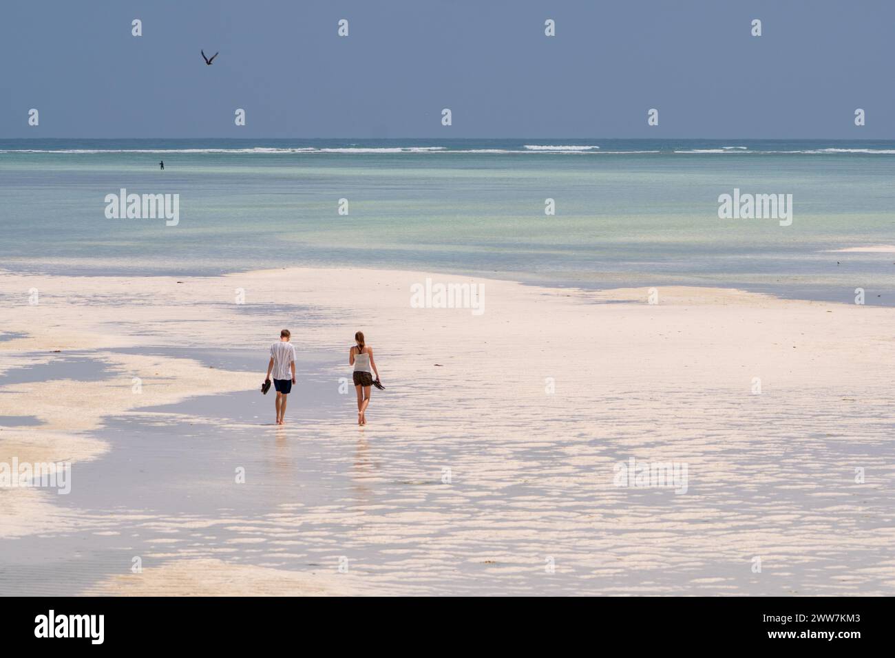 Touristen spazieren am Strand bei Sonnenuntergang. Fotografiert an der Ostküste Sansibars Stockfoto