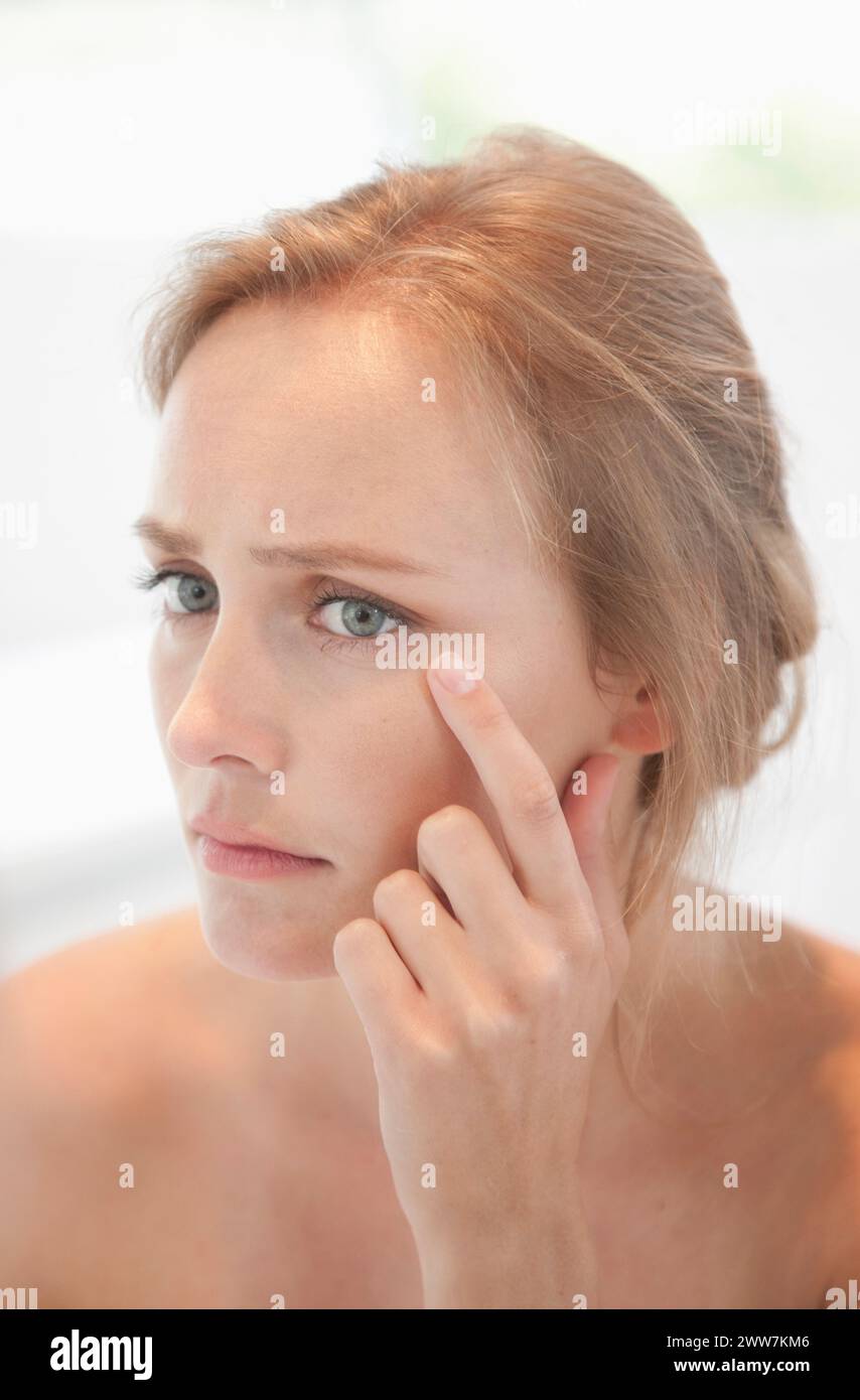 Ihr Gesicht betrifft Frau auf der Suche im Spiegel überprüfen Stockfoto