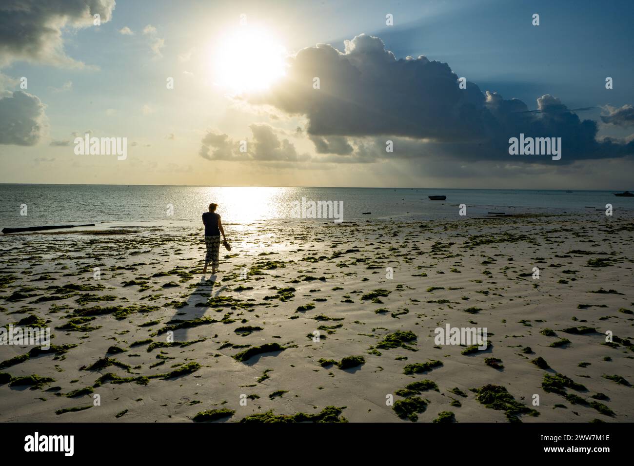 Touristen spazieren am Strand bei Sonnenuntergang. Fotografiert an der Ostküste Sansibars Stockfoto