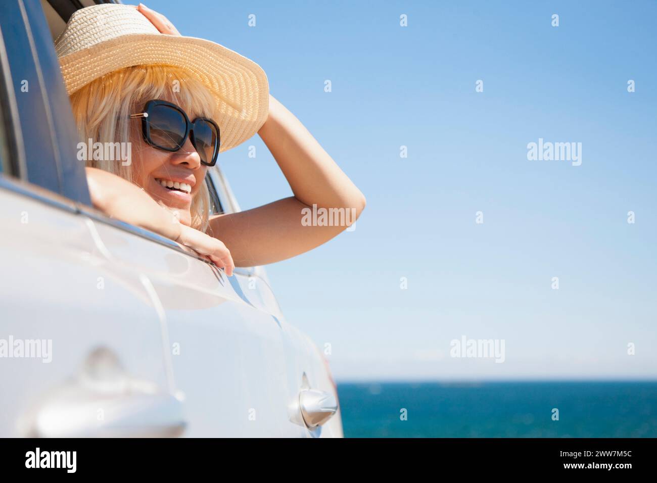 Suche Frau aus Autofenster, Ozean im Hintergrund Stockfoto