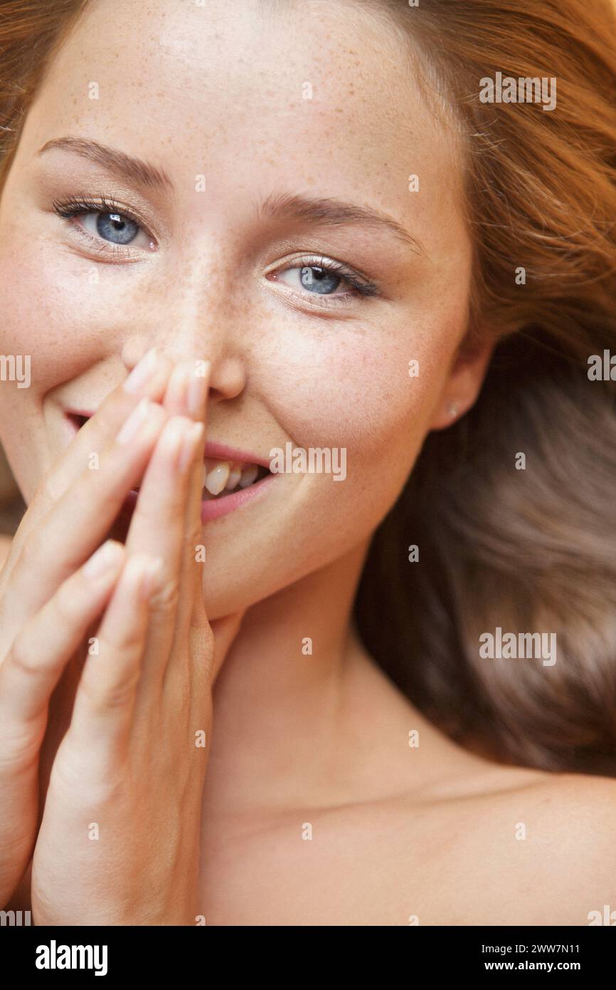 Junge Frau mit Händen über lächelnden Mund Nahaufnahme Stockfoto