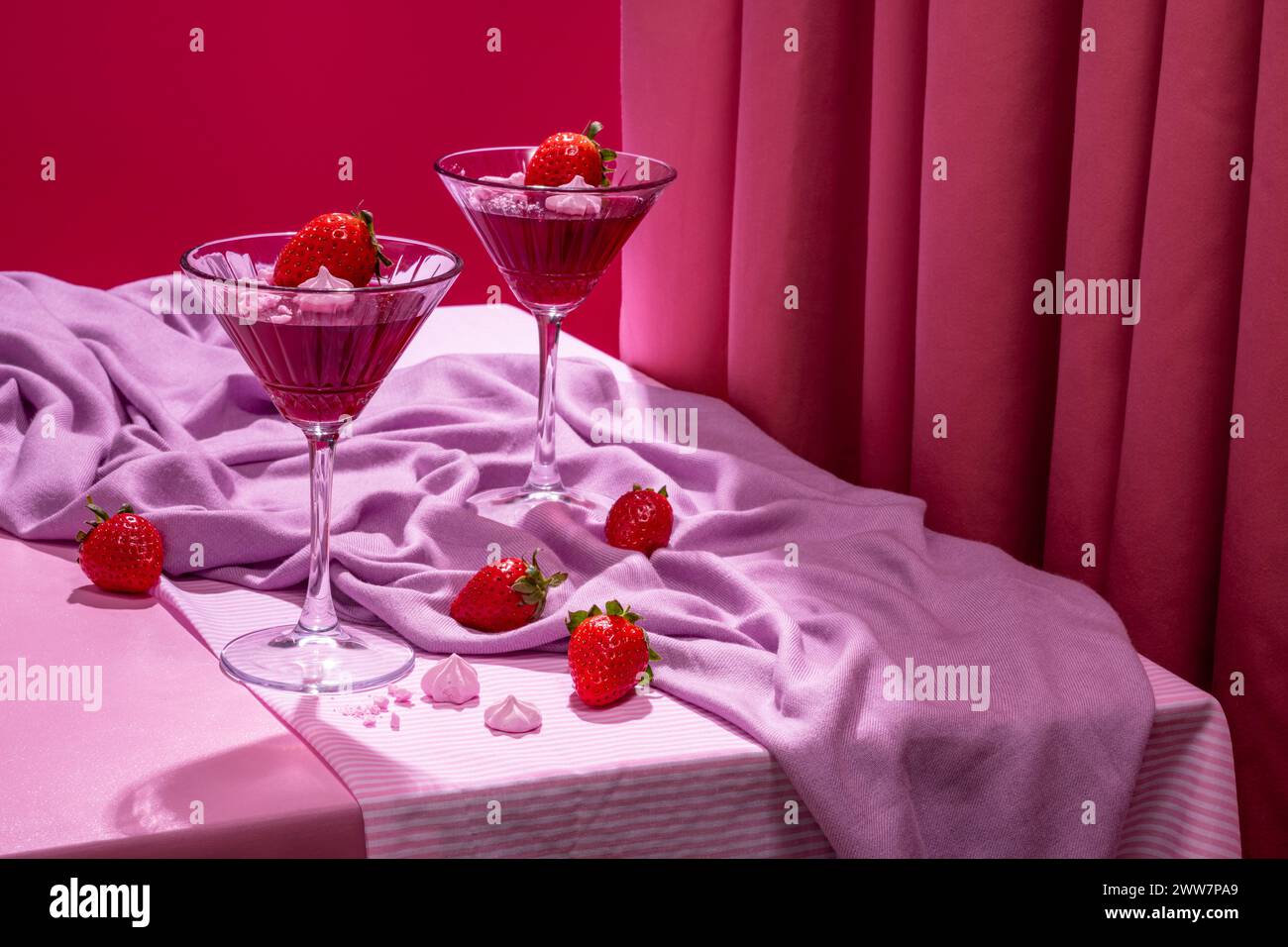 Erdbeer-Gelee und Meringue-Dessert in einem dekorierten hohen Glas in einer romantischen rosa Szene Stockfoto