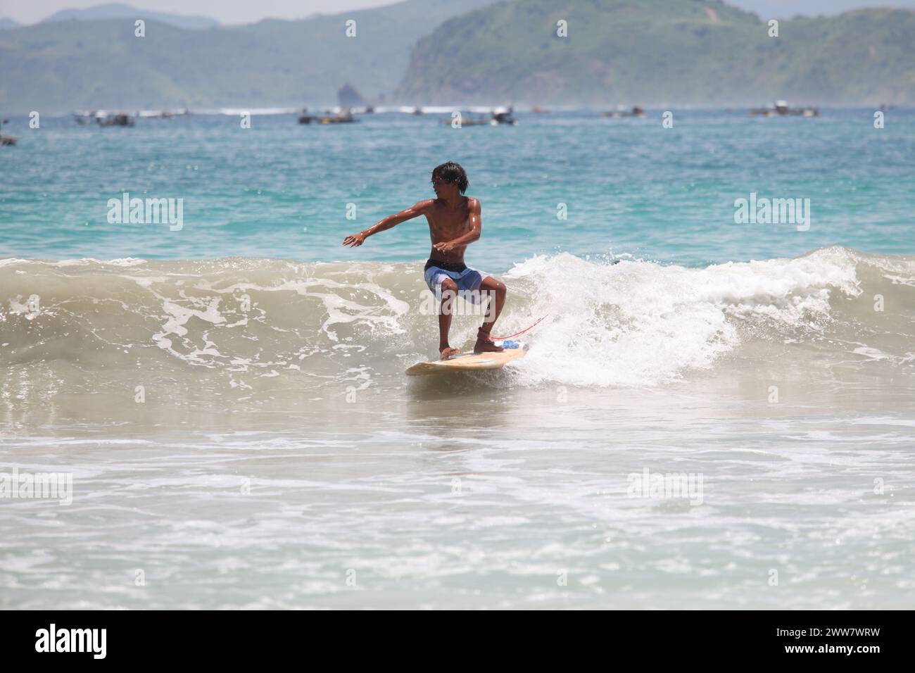 Ein Surfer genießt die starken Wellen am Strand mit seinem Surfbrett mit absoluter Ruhe und Konzentration und voller Zuversicht, das ist sehr angenehm Stockfoto