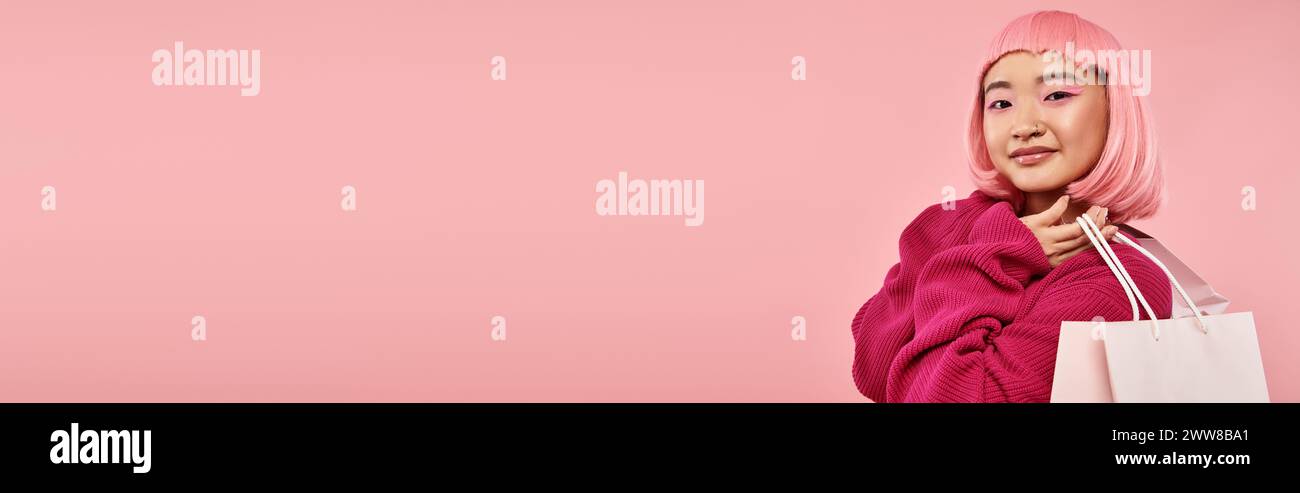 Horizontale Ansicht einer attraktiven asiatischen Frau in 20ern, die mit Päckchen vor rosa Hintergrund posiert Stockfoto