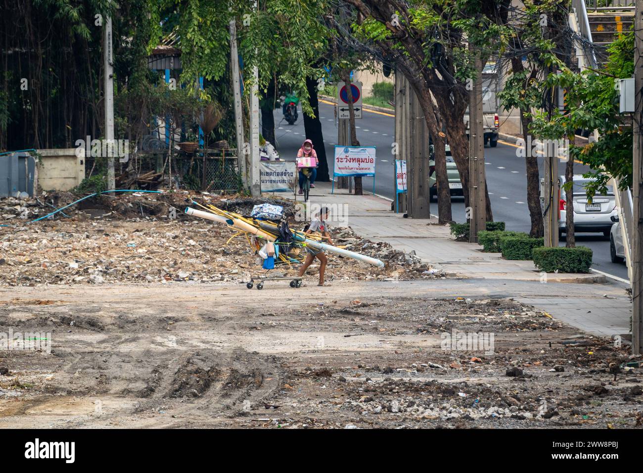 Bangkok, Thailand. März 2024. Eine weibliche Müllpflückerin wird gesehen, wie sie auf der Lat Phrao Road in Bangkok ein gereinigtes Land mit einem Supermarktwagen voller gesammeltem Müll, einschließlich Wasser- und elektrischen Kunststoffrohren, verlässt. Bangkoks Müllsammler oder Salengs, meist ältere Menschen, spielen eine wichtige Rolle in der Kreislaufwirtschaft der Stadt, indem sie Straßenmüll sammeln. Trotz ihres Beitrags leiden sie unter Armut, Unsicherheit, Gesundheitsrisiken und Stigmatisierung. (Credit Image: © Nathalie Jamois/SOPA Images via ZUMA Press Wire) NUR REDAKTIONELLE VERWENDUNG! Nicht für kommerzielle ZWECKE! Stockfoto