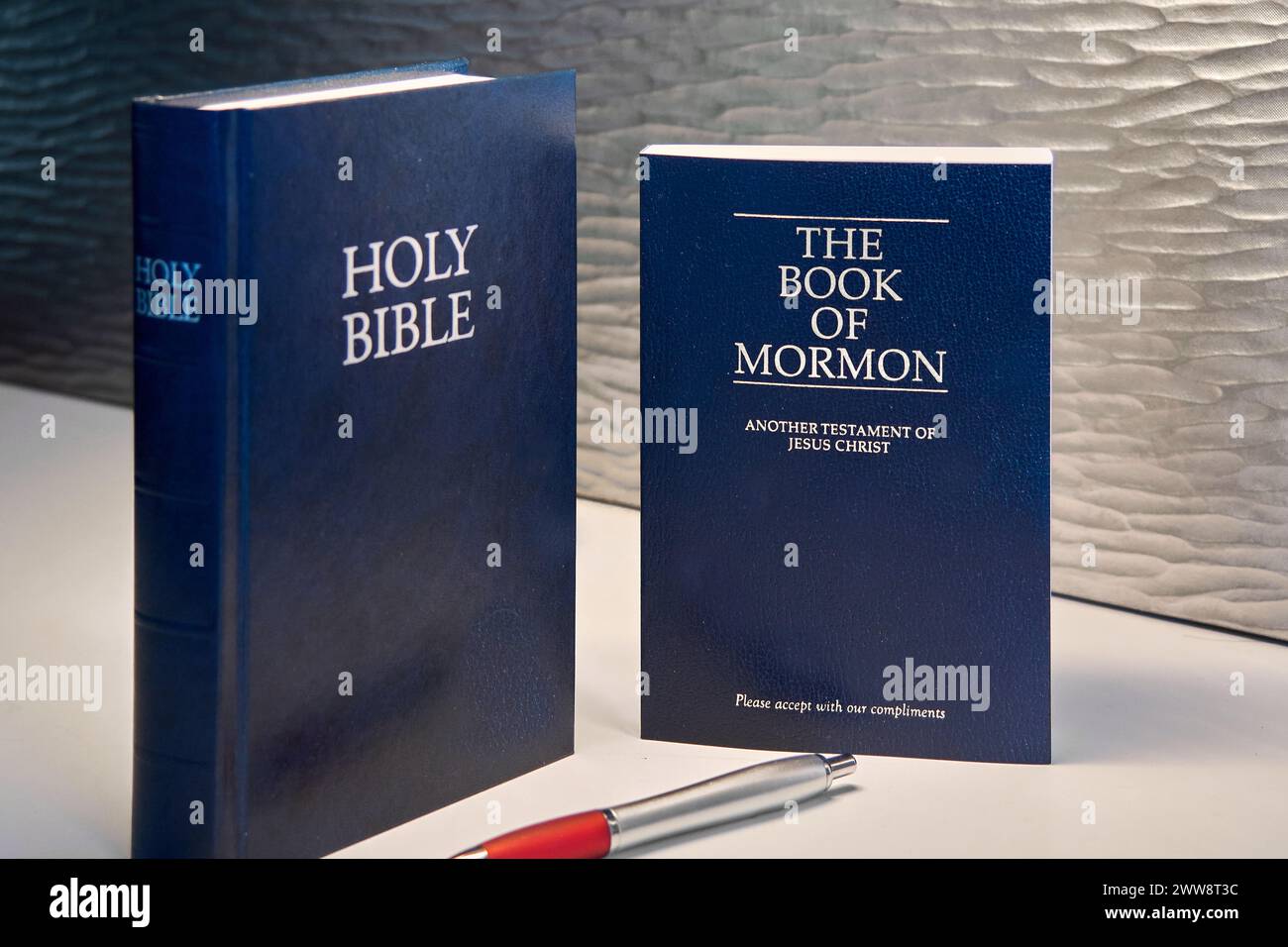 Dieses Bild zeigt eine Bibel und ein Buch Mormon, beide in dunklen Tönen, begleitet von einem roten und silbernen Stift, es ist ideal für religiöse Themen, Studien und Re Stockfoto