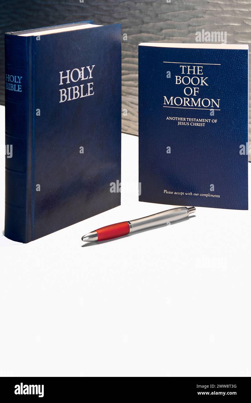 Dieses Bild zeigt eine Bibel und ein Buch Mormon, beide in dunklen Tönen, begleitet von einem roten und silbernen Stift, es ist ideal für religiöse Themen, Studien und Re Stockfoto