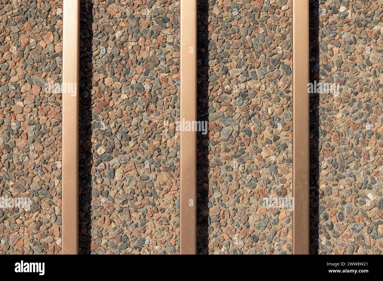 Hintergrund der Wand aus Beton und Kieselstein mit Metallstäben aus Bronze Stockfoto