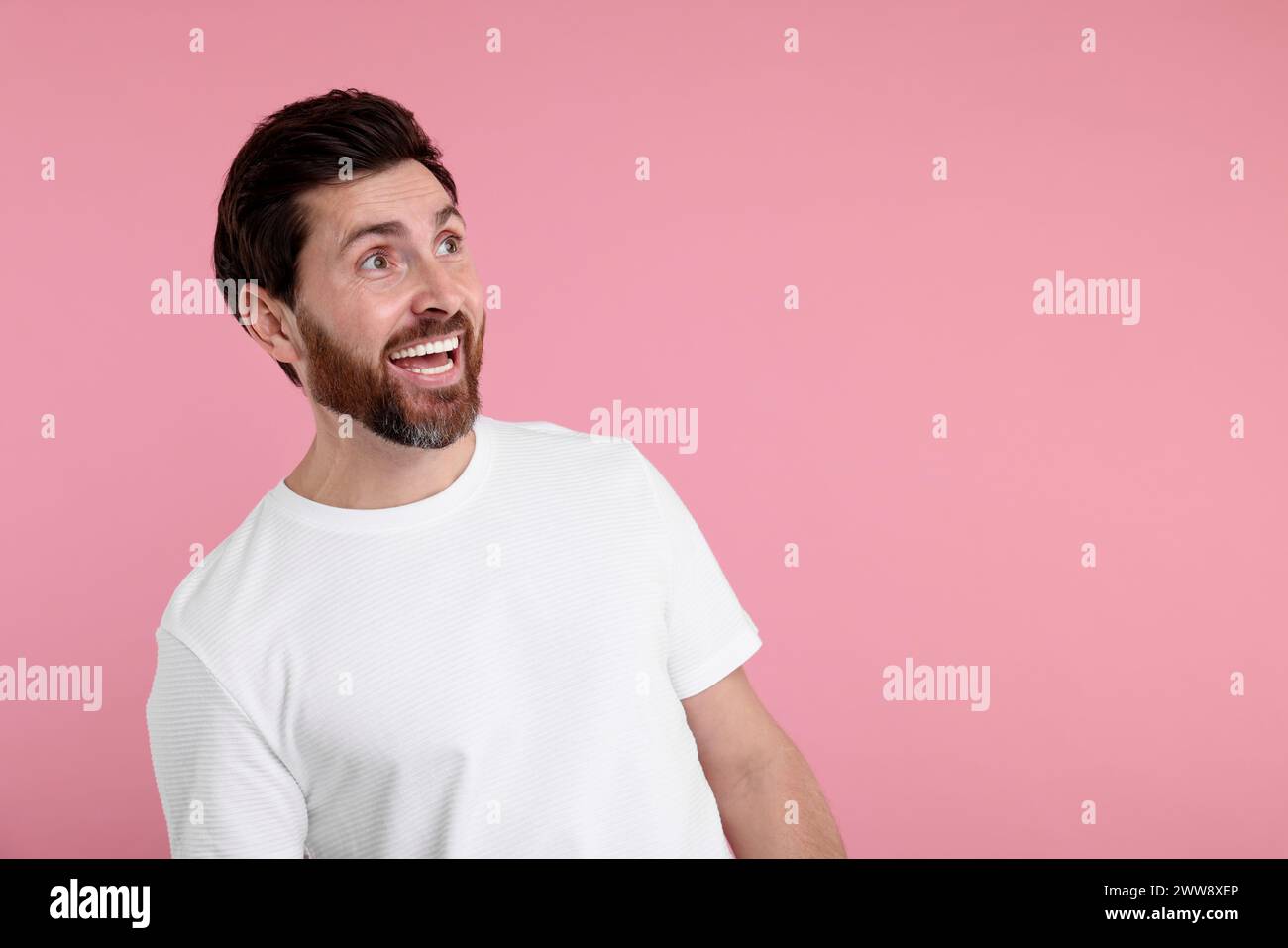 Porträt des glücklichen überraschten Mannes auf rosa Hintergrund, Platz für Text Stockfoto