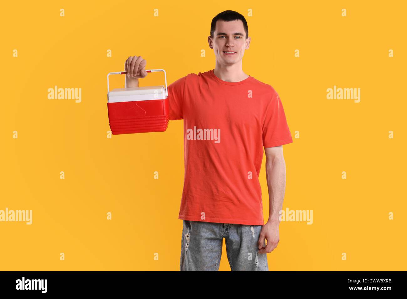 Mann mit roter Kühlbox auf orangem Hintergrund Stockfoto