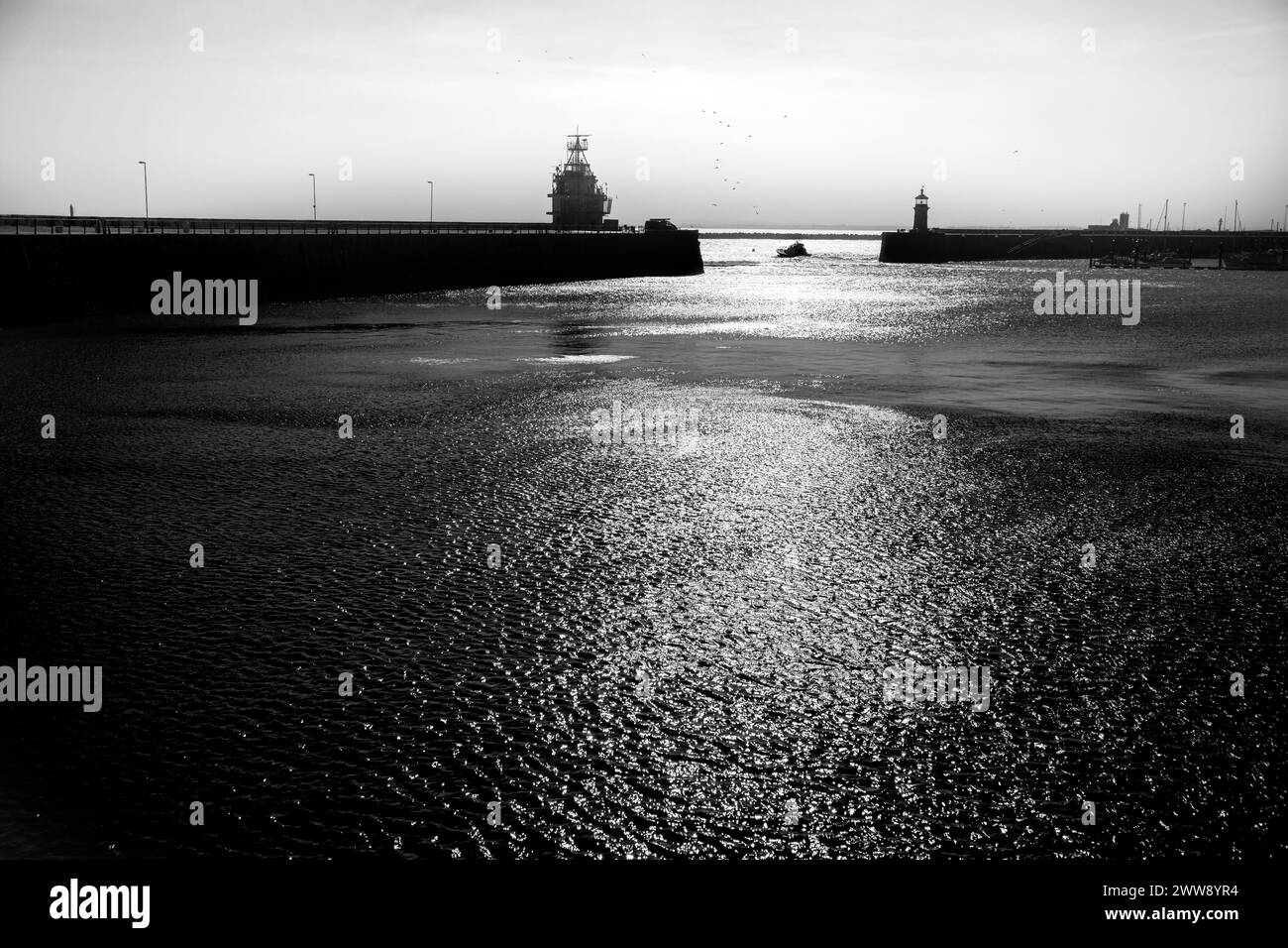 Ein kleines Vergnügungsboot, das aus dem Hafen von Ramsgate fährt, mit der niedrigen Sonne, die vom Wasser reflektiert wird. Enthält Platz für Text Stockfoto