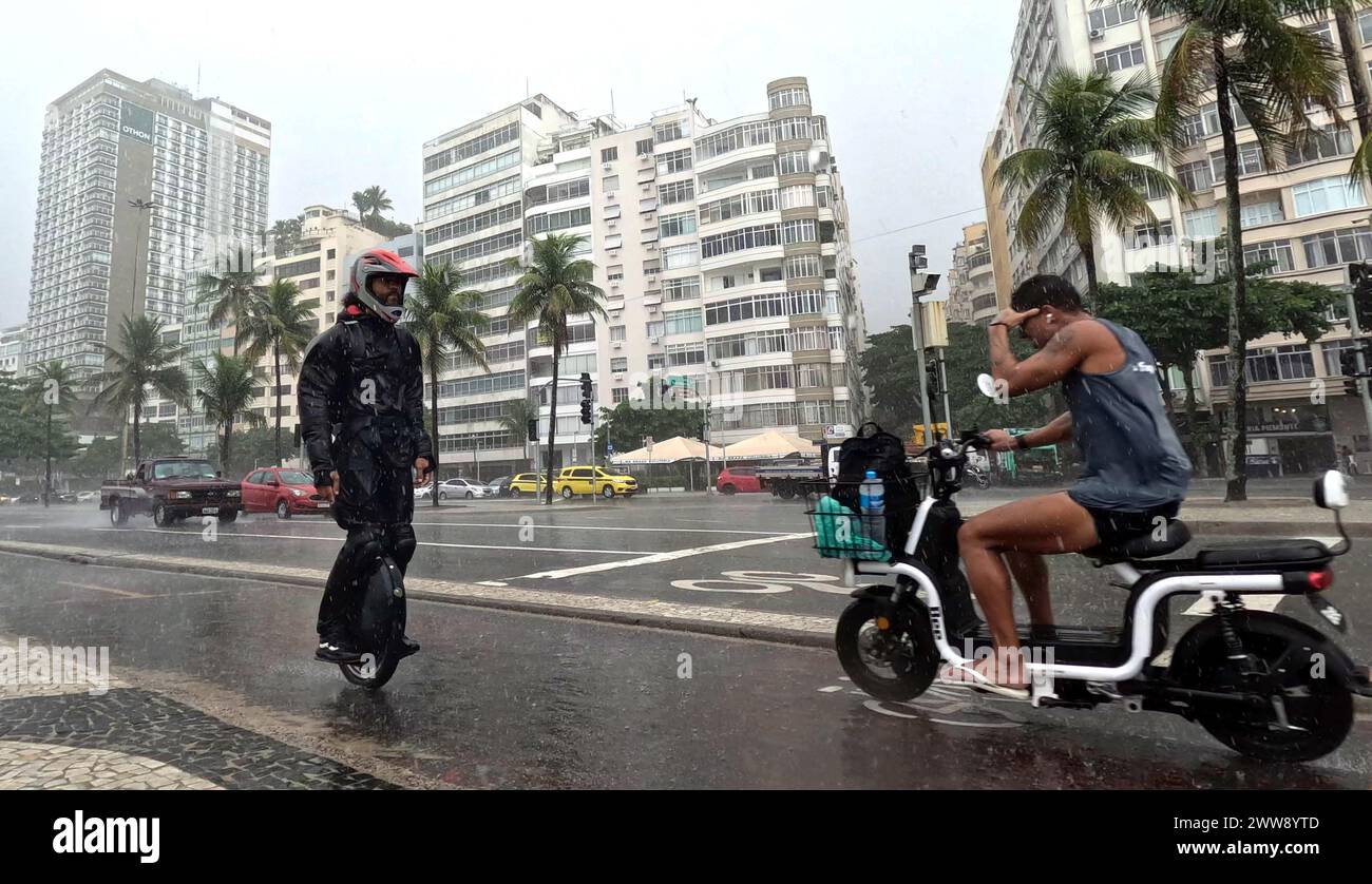 Copacabana, Rio De Janeiro, Brasilien. März 2024. Ein Mann in einem Helm rotet ein motorisiertes Einrad, als er an einem Roller vorbeifährt. Die Bewohner von Rio de Janeiro trotzen dem Sturm entlang der Promenade am Copacabana Beach, inmitten eines Regenschusses, der von einer kalten Front durch Rio de Janeiro ausgelöst wird. Mit starkem Regen und drohenden Unterbrechungen hält die Stadt bis Sonntag bis zu 6 cm Niederschlag bereit. (Credit Image: © Bob Karp/ZUMA Press Wire) NUR REDAKTIONELLE VERWENDUNG! Nicht für kommerzielle ZWECKE! Quelle: ZUMA Press, Inc./Alamy Live News Stockfoto