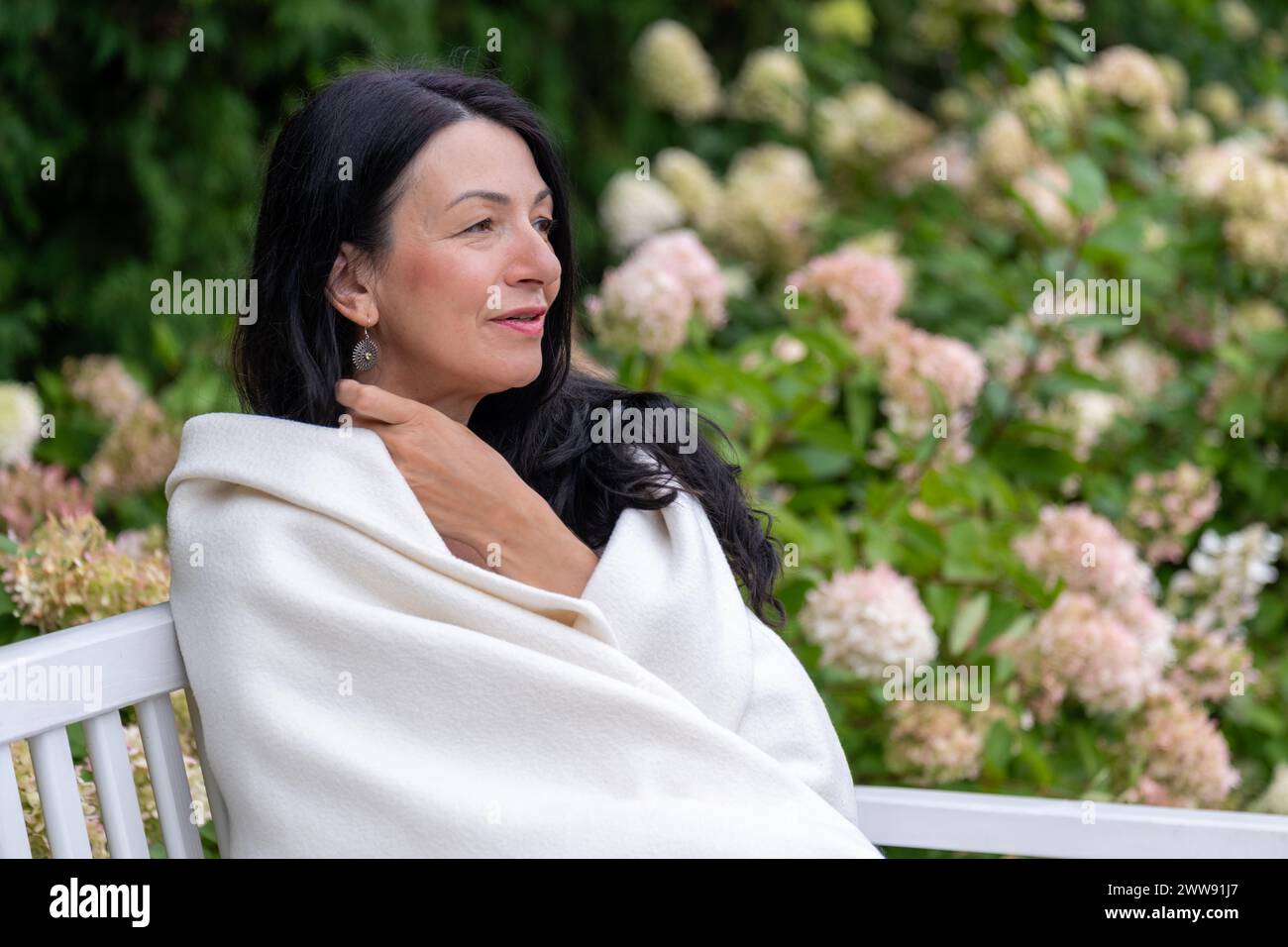 Eine reife Frau, warm gewickelt, blickt in die Ferne, ihr Ausdruck ist friedliche Selbstakzeptanz während des Lebensübergangs im Mittelalter. Hohe qu Stockfoto