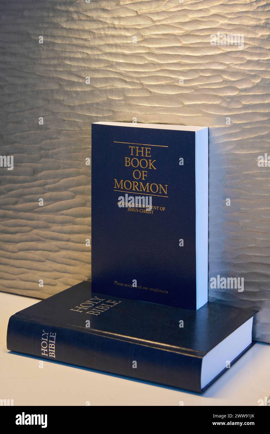 Das Buch Mormon und die Heilige Bibel stapelten sich, sanft beleuchtet vor einem strukturierten Hintergrund, was eine Atmosphäre der Ruhe und Ehrfurcht hervorruft, i Stockfoto