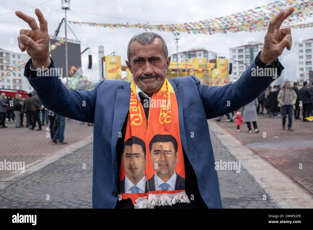 Ein alter Mann, der einen Schal mit Fotos des inhaftierten kurdischen Politikers Selahattin Demirtas trägt, macht Siegeszeichen. Tausende von Menschen versammelten sich in Diyarbakir und feierten Newroz, das als die Ankunft des Frühlings und des neuen Jahres des persischen Kalenders gilt. Sie füllten den Newroz Park mit grünen, roten und gelben Fahnen und hatten Spaß beim Singen kurdischer Lieder. Stockfoto