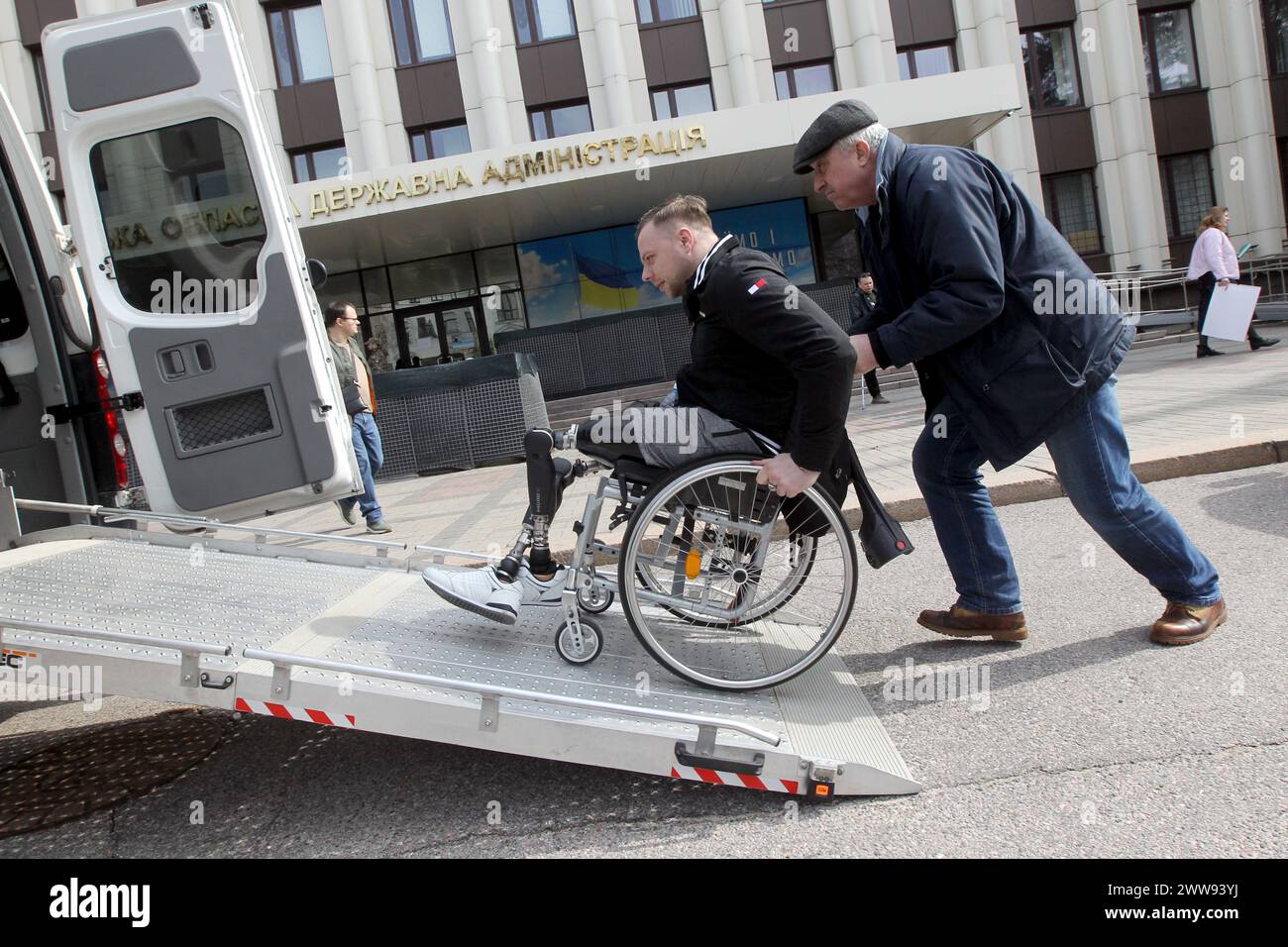 Nicht exklusiv: DNIPRO, UKRAINE - 21. MÄRZ 2024 - Ein Veteran in einem Rollstuhl mit prothetischen unteren Gliedmaßen wird dabei geholfen, in einem Spezialfahrzeug Platz zu nehmen Stockfoto