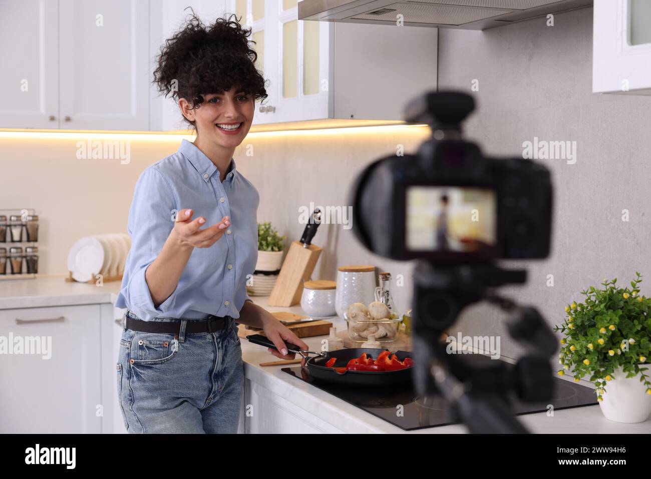 Lächelnder Food-Blogger kocht während der Videoaufnahme in der Küche Stockfoto