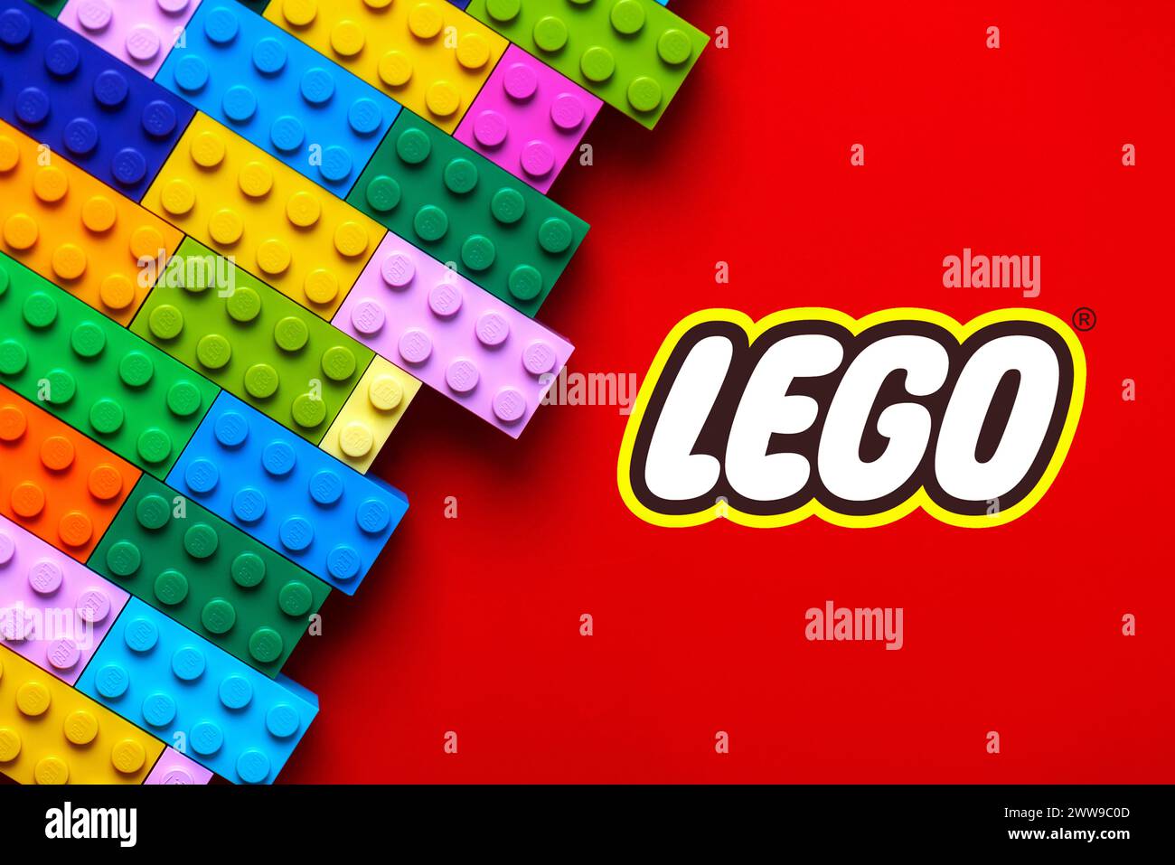 Nahaufnahme von bunten Lego-Blöcken mit dem Lego-Logo auf rotem Hintergrund. Illustrativer Leitartikel Stockfoto