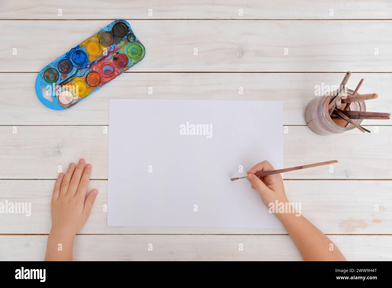 Die Hände verwenden einen Pinsel für Aquarellmalerei auf sauberem Papier. Vorstellung von Kreativität, Kunst, Kindheit, Fantasie und künstlerischem Ausdruck Stockfoto