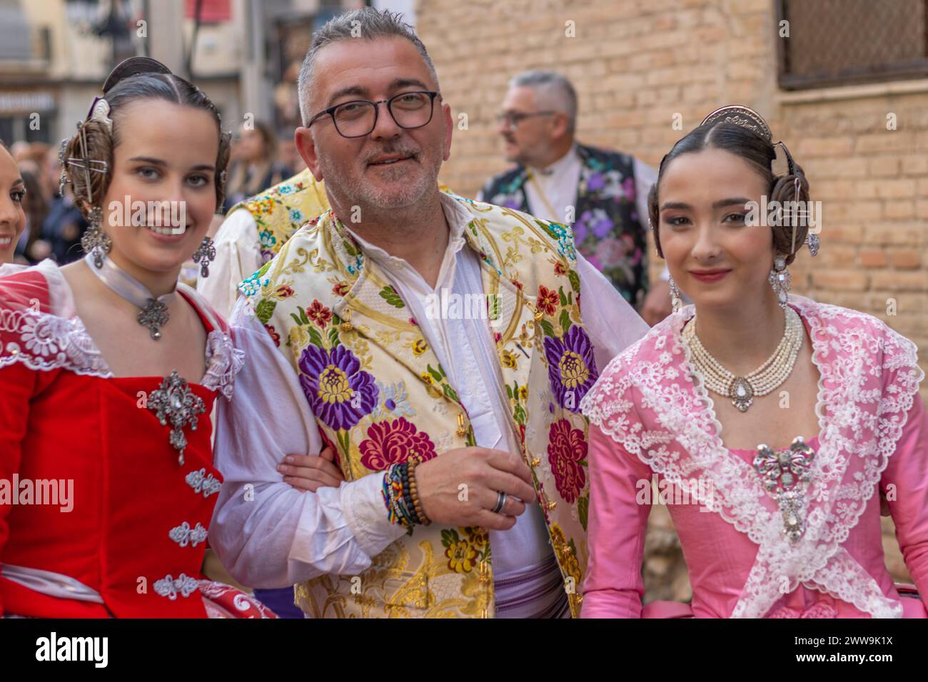 Gandias Straßen werden mit den traditionellen Trachten Valencias lebendig. Die komplizierten Designs und festlichen Farben zelebrieren ein reiches kulturelles Erbe Stockfoto