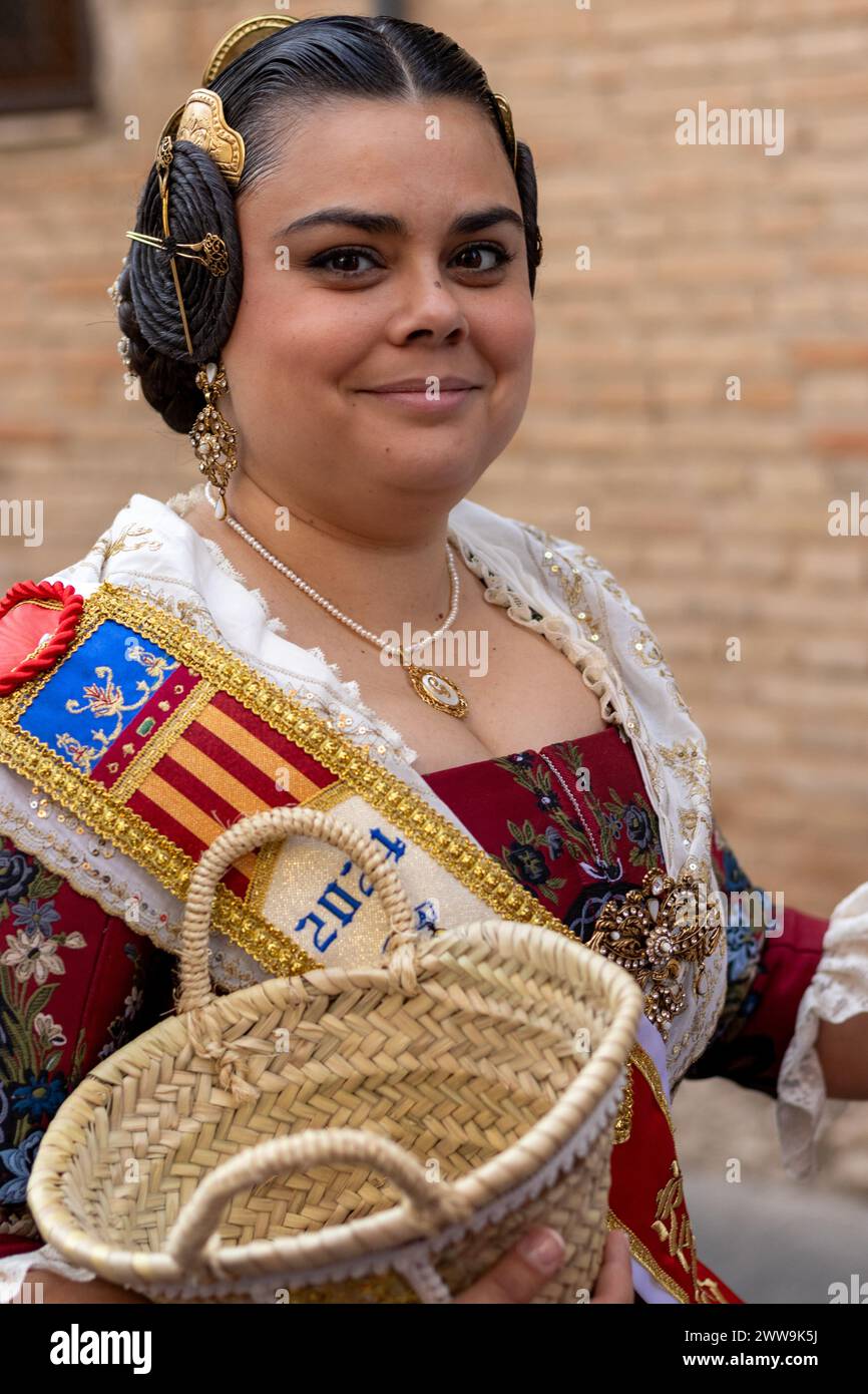 Valencianische Eleganz im Vollformat. Die Kleidung einer Fallera, reich an Rot und weiß mit goldenen Akzenten, fängt den Geist von Gandias Fallas-Festival ein. Stockfoto