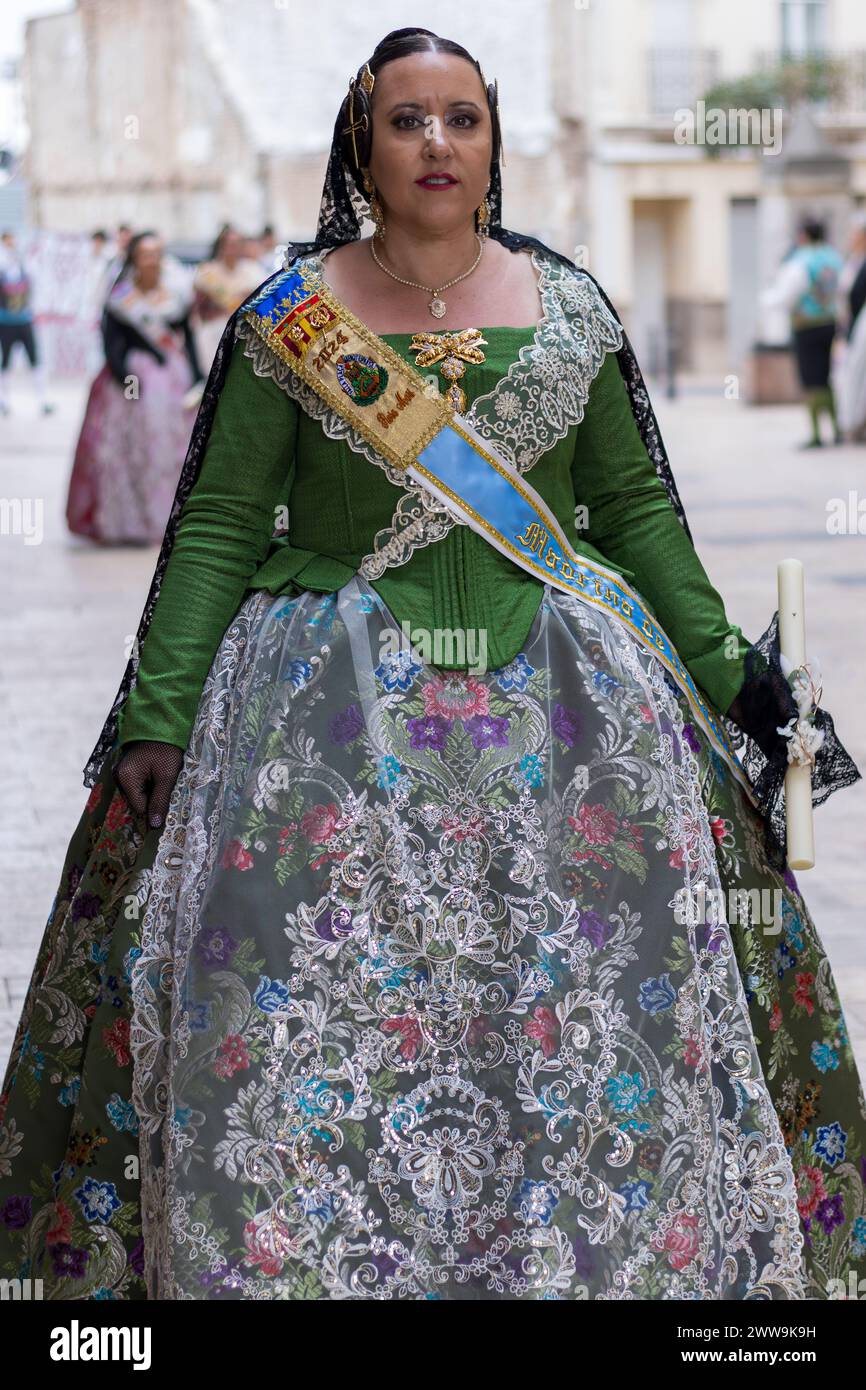 Eine Frau in traditioneller valencianischer Kleidung feiert das lebhafte Festival in Gandia. Ihr grünes Kleid, das mit Blumenmustern verziert ist, spiegelt die reiche Kuh wider Stockfoto