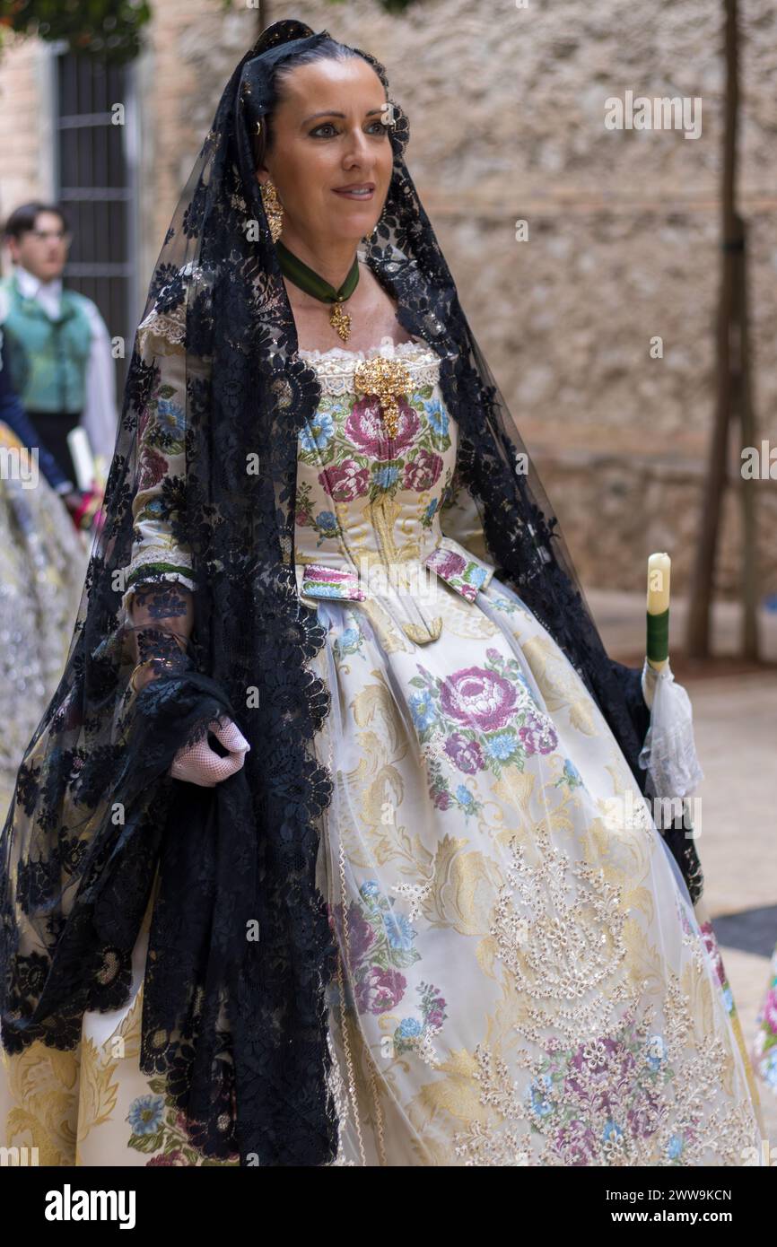 Eine Frau in traditioneller Kleidung feiert das Fallas Festival in Gandia, ihr Kleid ist eine lebendige Hommage an das Erbe. Stockfoto