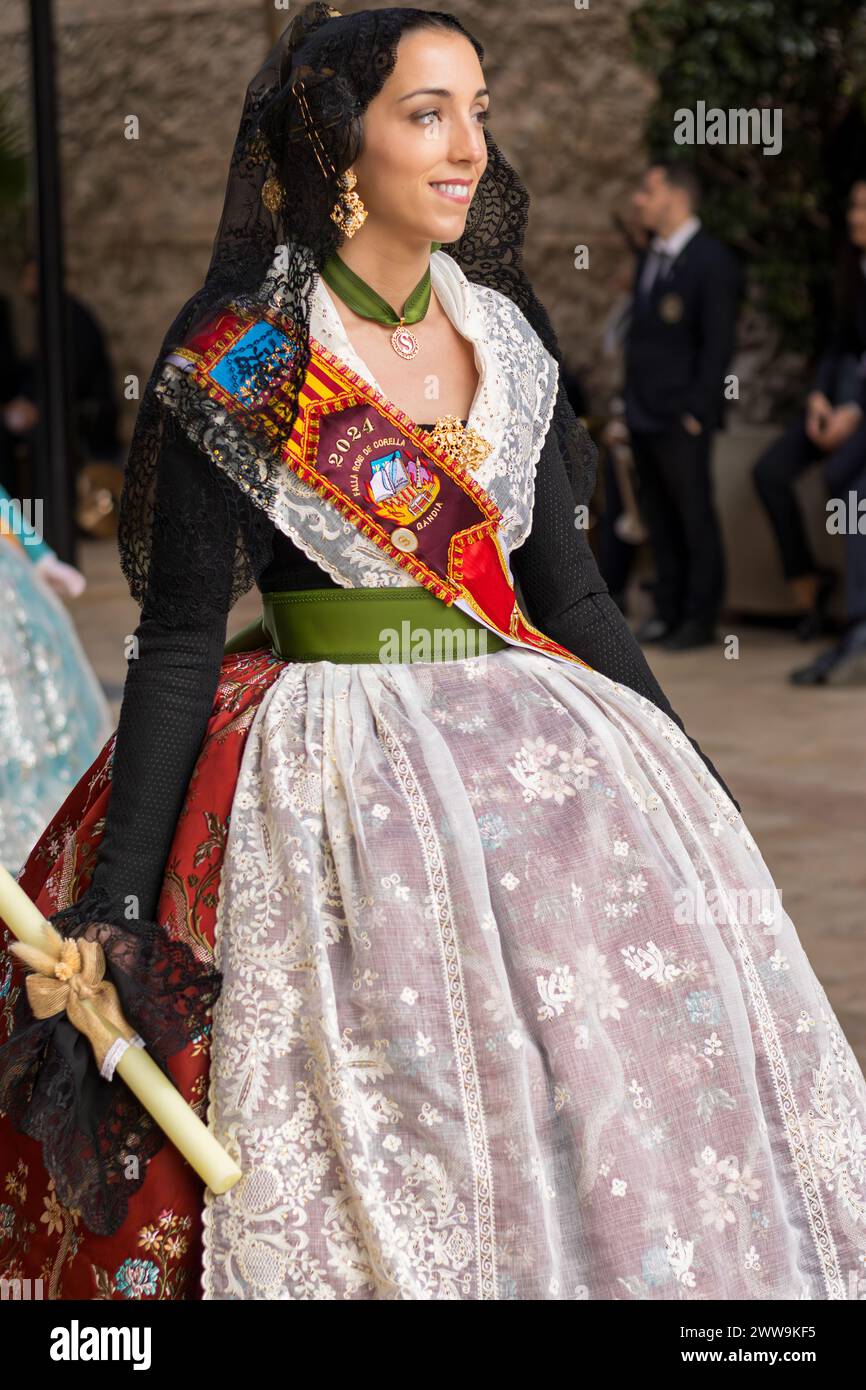 Festliche Eleganz in Gandias Fallas: Die traditionelle Pracht einer Frau. Ihr Kostüm, eine lebendige Feier des Erbes, glitzert in der Sonne Valencias. Stockfoto
