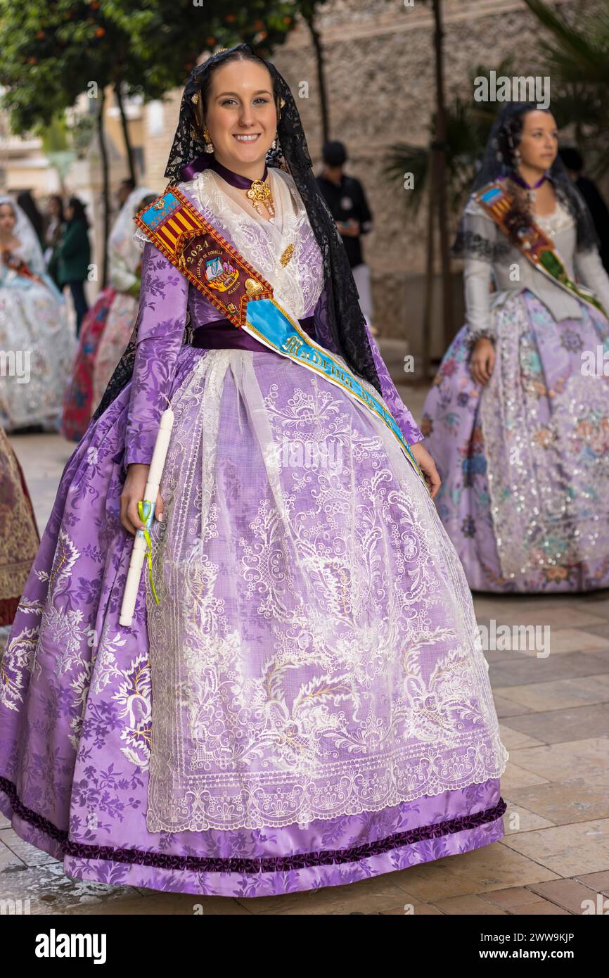 Valencianische Eleganz inmitten von Gandias festlicher Luft. Das Kostüm der Fallera, eine lebendige Feier der Tradition, verzaubert mit seinen reichen Wandteppichen und cultura Stockfoto