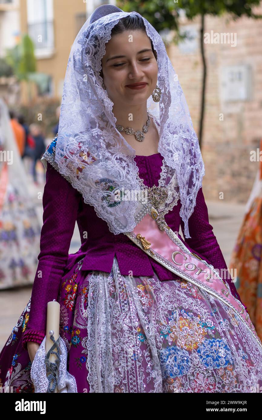 Valencianische Eleganz entfaltet sich, während eine Frau in Fallas-Kleidung die Festlichkeiten in Gandia ziert. Ihr Kostüm, eine lebendige Hommage an die Tradition, webt ein visuelles Bild Stockfoto